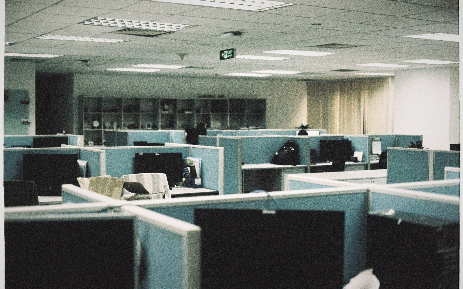 An empty open-plan office lit only by monitors