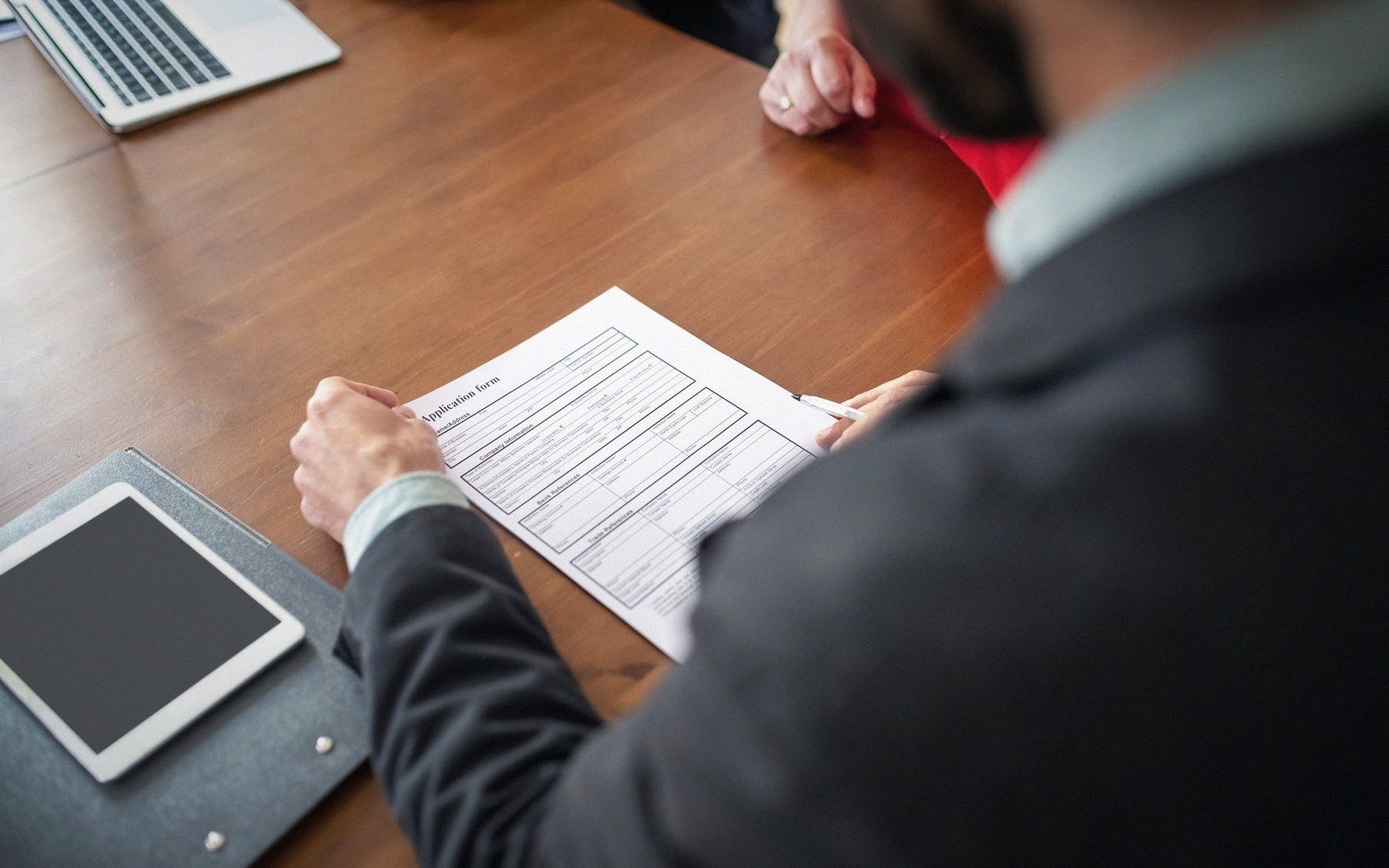 Man in a suit filling out an application form at a wooden desk