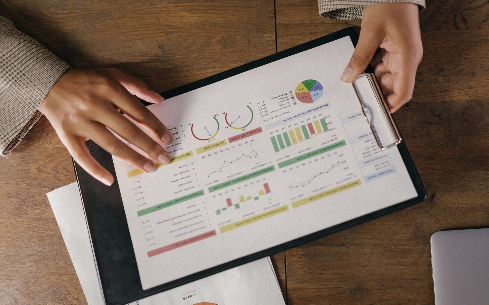Two hands hold a clipboard displaying charts and graphs on a printed report