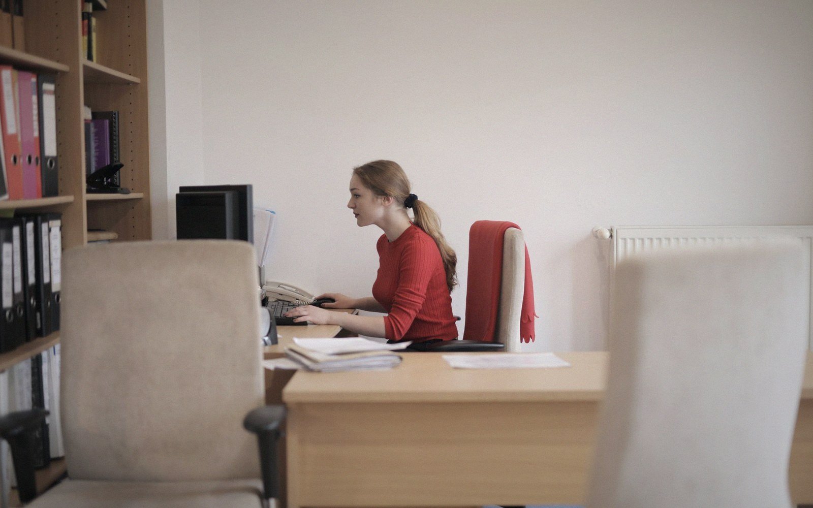 Woman in a red top typing on a computer at an office desk