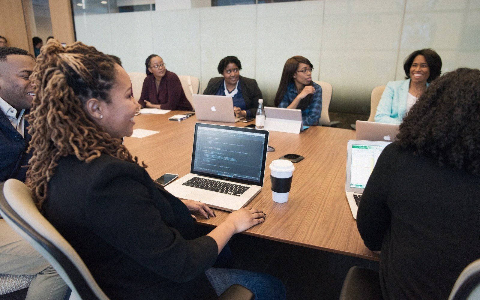 Colleagues gather around a conference table with laptops during a business meeting